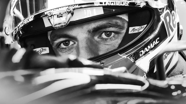Max Verstappen wearing his racing helmet in the cockpit.